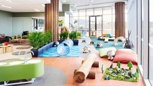 Comprehensive view of Guardian Childcare Springfield's vibrant indoor play area, showcasing diverse learning zones including a tunnel, ride-on toys, water station, reading nook, and dinosaur play, designed for holistic early childhood development.