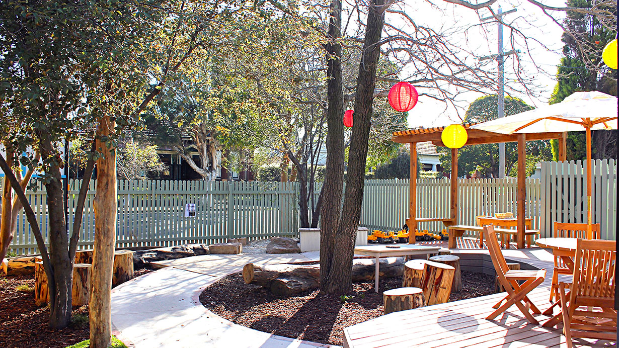 Trees provide shade over a garden and outdoor play area with pergola.