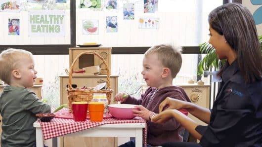 2 children sitting eating with an educator at Guardian Moorabbin childcare centre in Melbourne