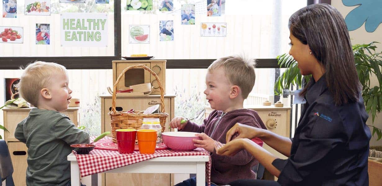 2 children sitting eating with an educator at Guardian Moorabbin childcare centre in Melbourne