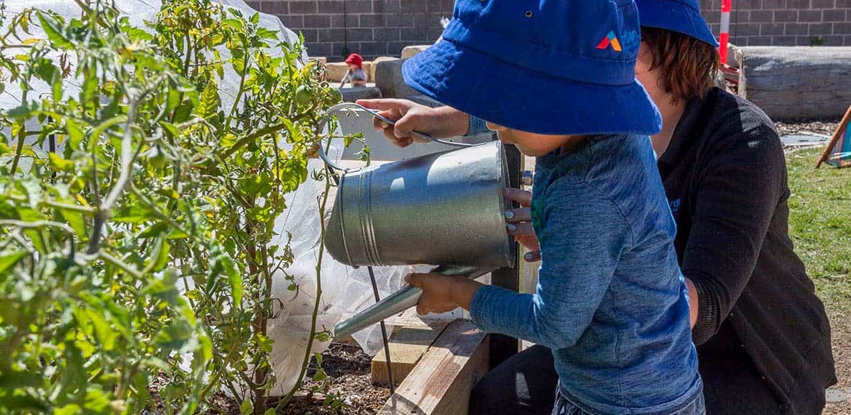 Child watering plant at Guardian Forde