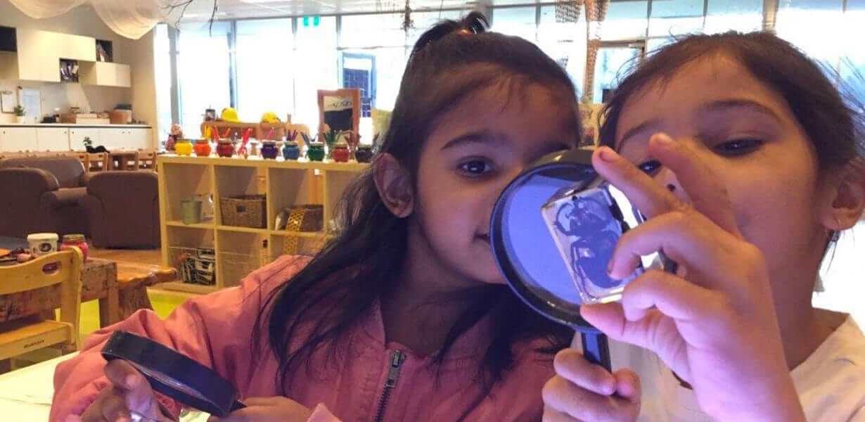 Two children from Guardian Underwood using a magnifying glass