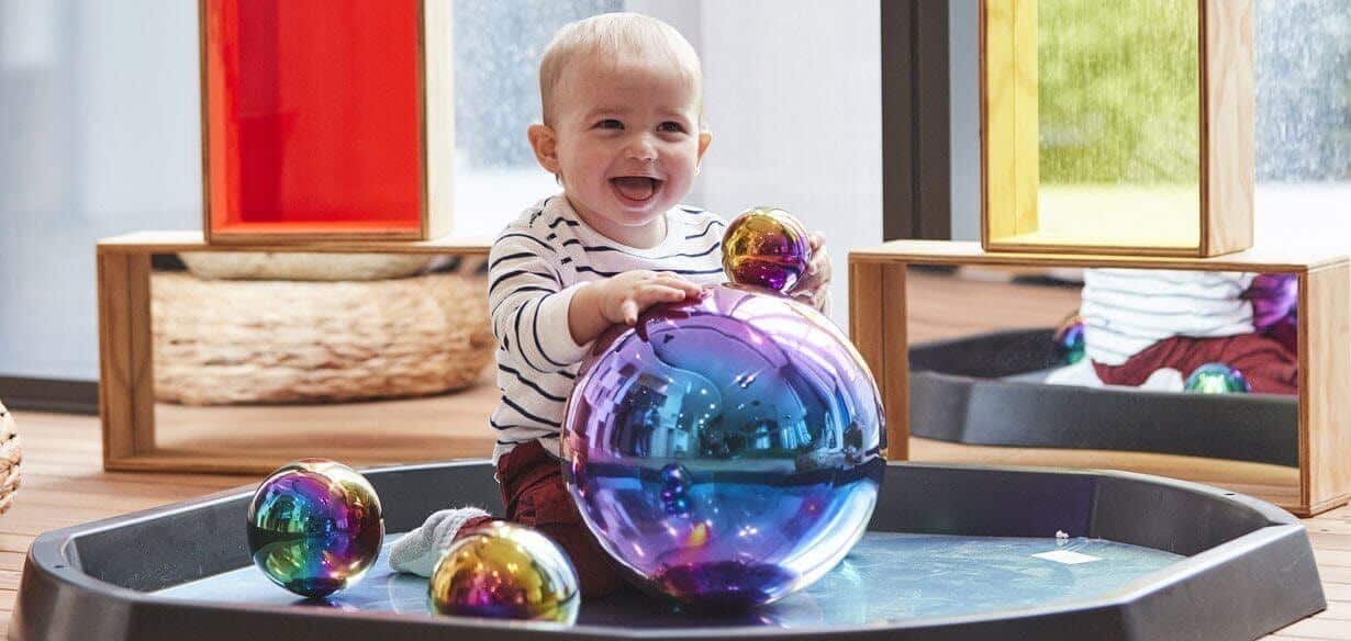 Baby touching large colourful dome and laughing