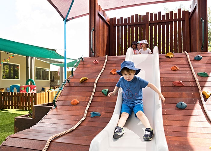 Child at Guardian Aspley going down slide in outdoor area