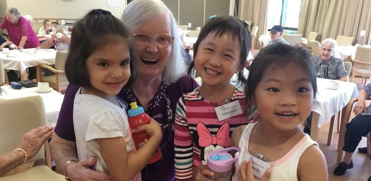 Three children from Guardian Sunnybank posing with elderly woman