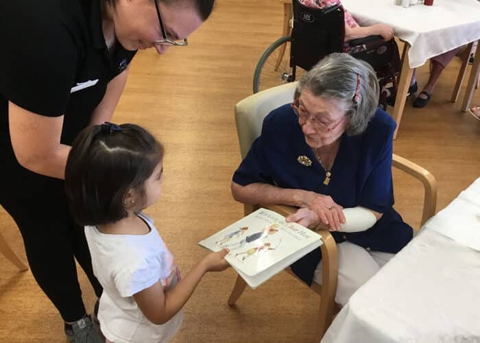 Child from Guardian Sunnybank holding book with elderly lady