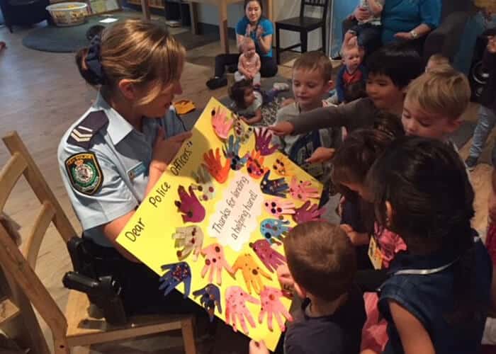 Guardian Macquarie Park children pointing at poster policewoman is holding up