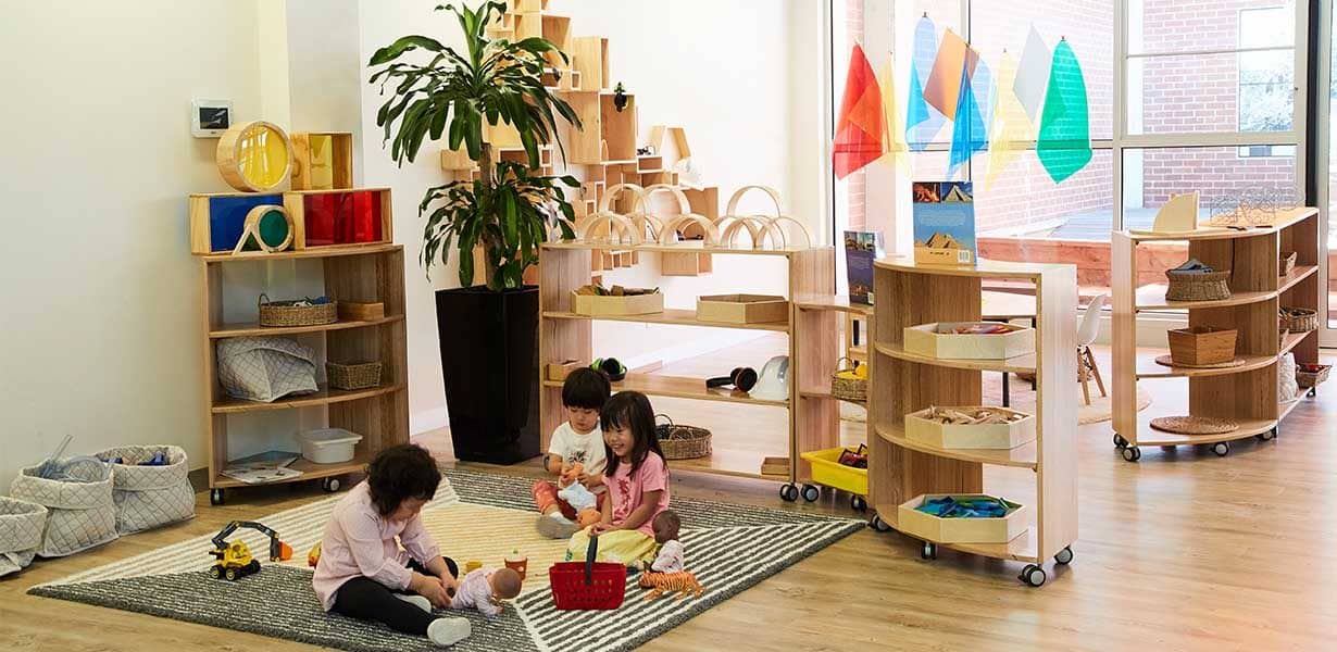 three children playing with dolls on floor at Guardian Marrickville