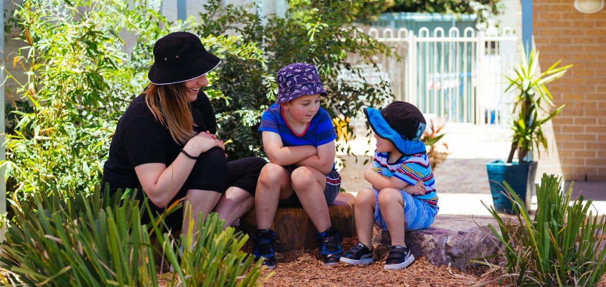 Educator and children sitting in garden at St Clair childcare