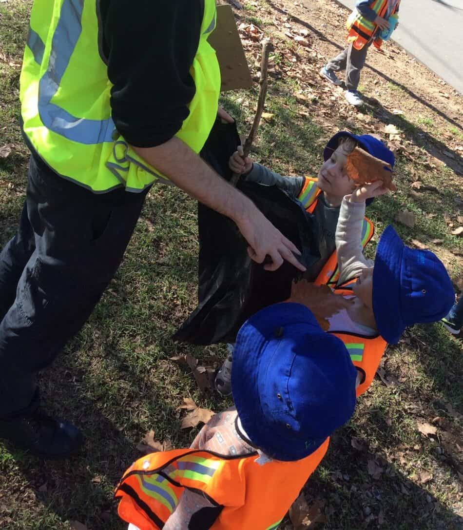 Children picking leaves and twigs with Educator
