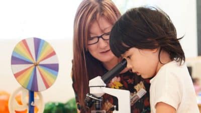 child with Educator looking through a microscope, curious, learning