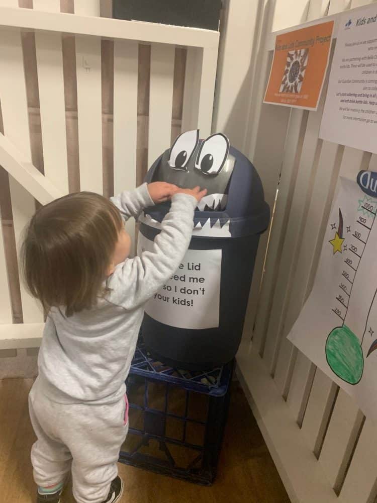 toddler adding plastic lids to Sid the Lid Monster