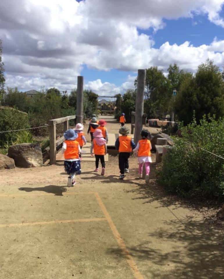 children walking in park wearing safety vests on an excursion