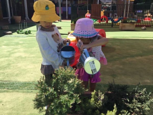 two children watering a garden