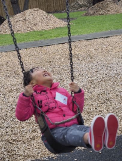 young girl on swing at park laughing on excursion program