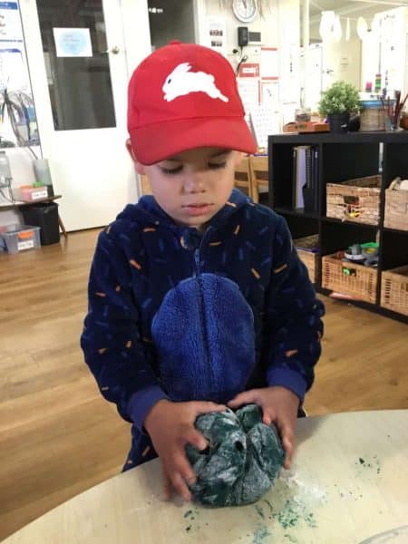 young boy in cap making planet out of play dough