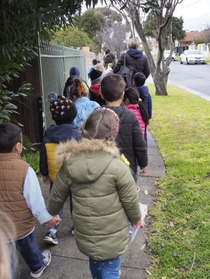 children holding hands and walking in line on excursion program