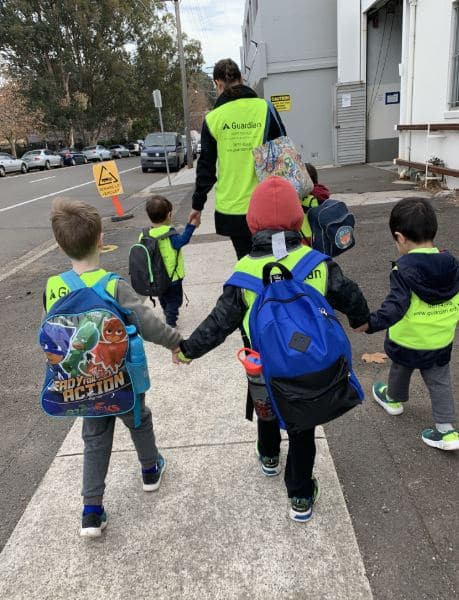 children in Guardian safety vests holding hands and walking to swimming lessons