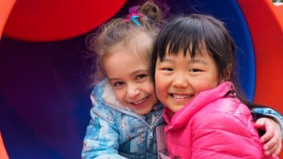two young girls hugging on a slide at excursion program