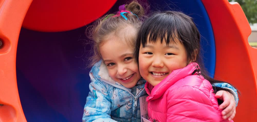 two young girls hugging on a slide at excursion program