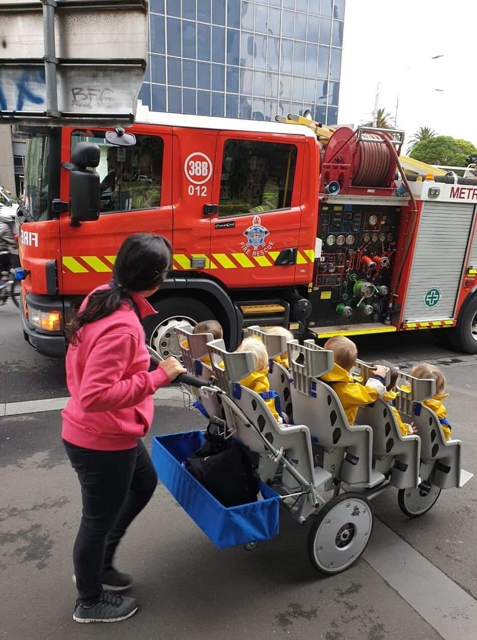 Educator pushing octopram past firetruck