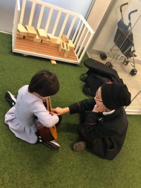 high school student teaches child to play guitar