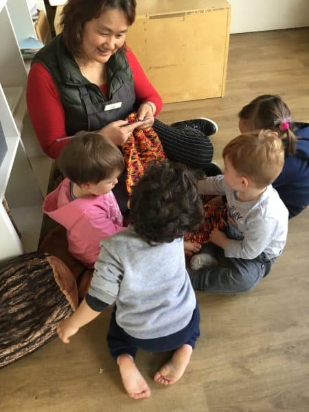 educator teaching a group of young children how to knit for yarn bombing project