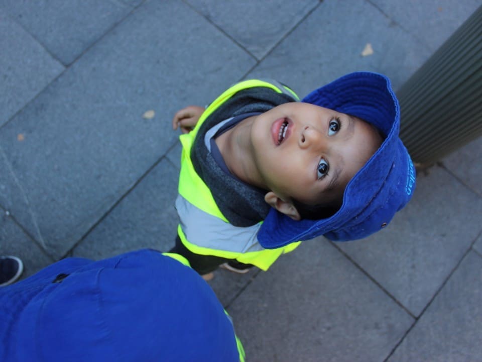 child in safety vest looking up at Sydney city