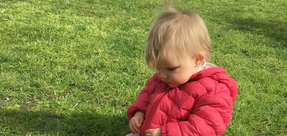 child playing in grass while on excursion with Octo-Pram