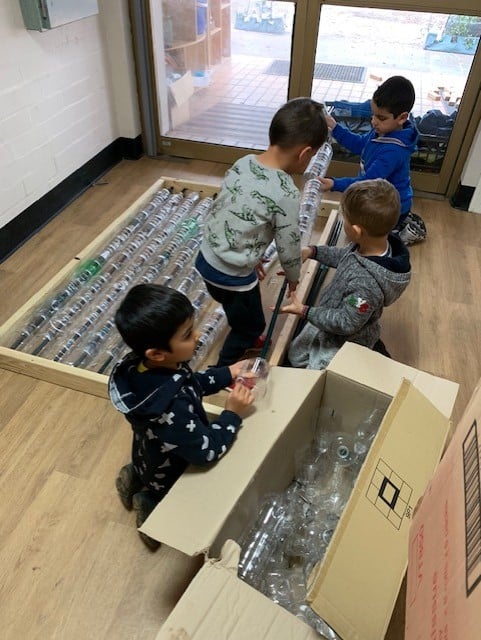 children assembling greenhouse out of plastic bottles