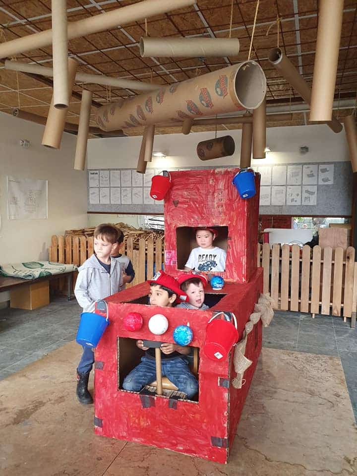 children playing in fire truck built out of recycled materials