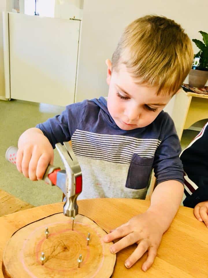 child hammering nails to build geoboards