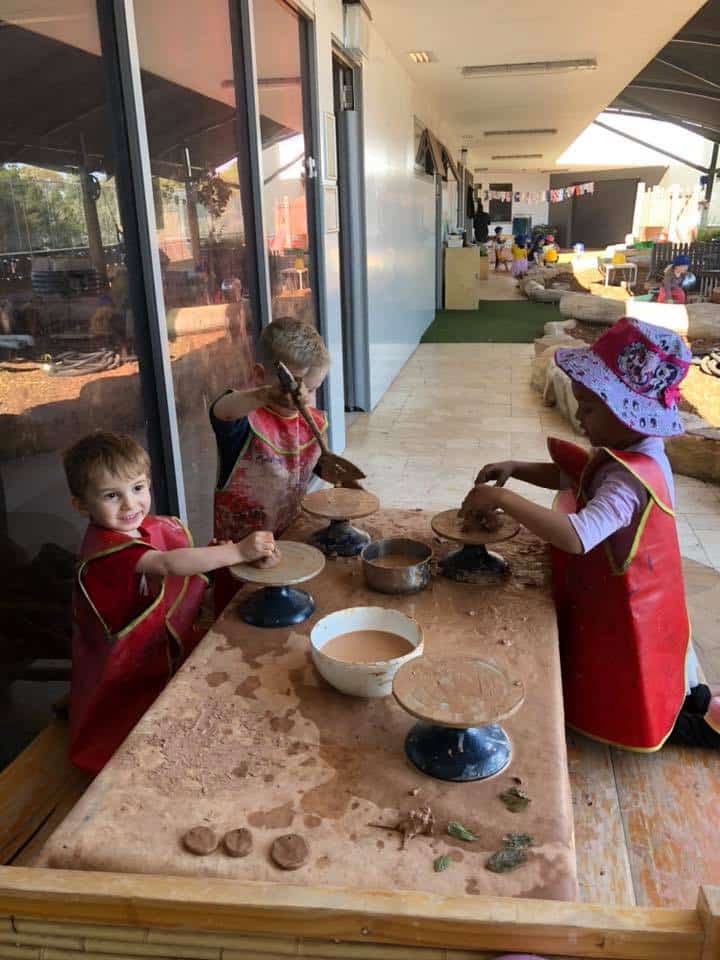 children wearing art smocks and creating with clay