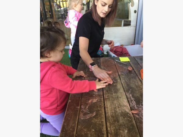 Educator and child rolling clay in sustainability program