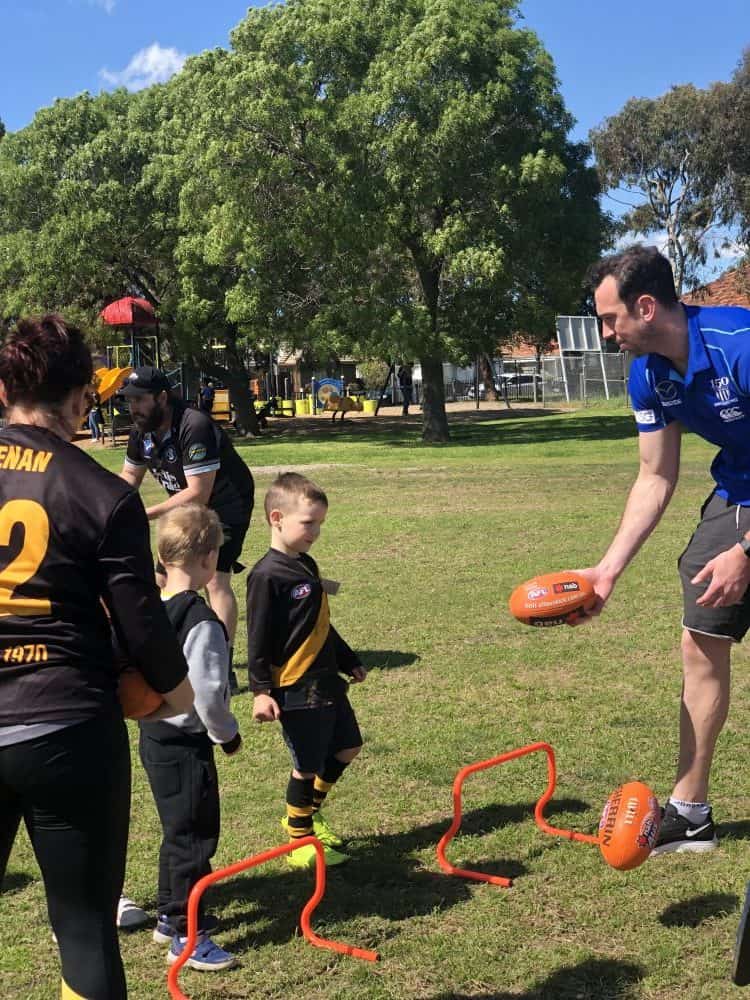 AFL player passing ball to child