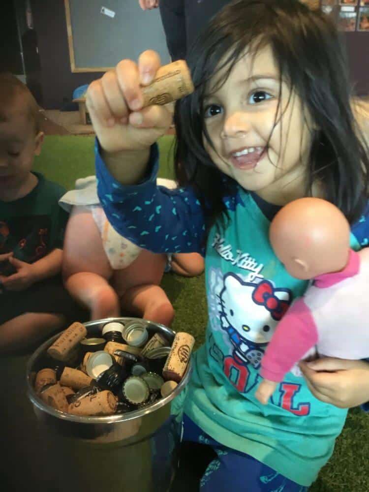 child holding toy baby and recyled cork