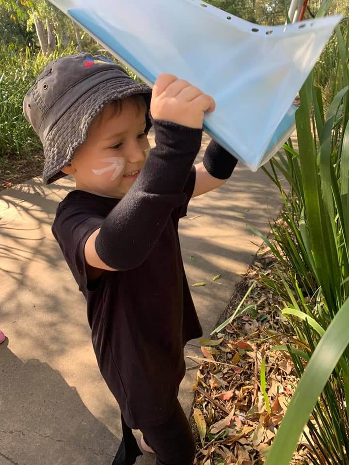 child placing book in garden for book hide and seek