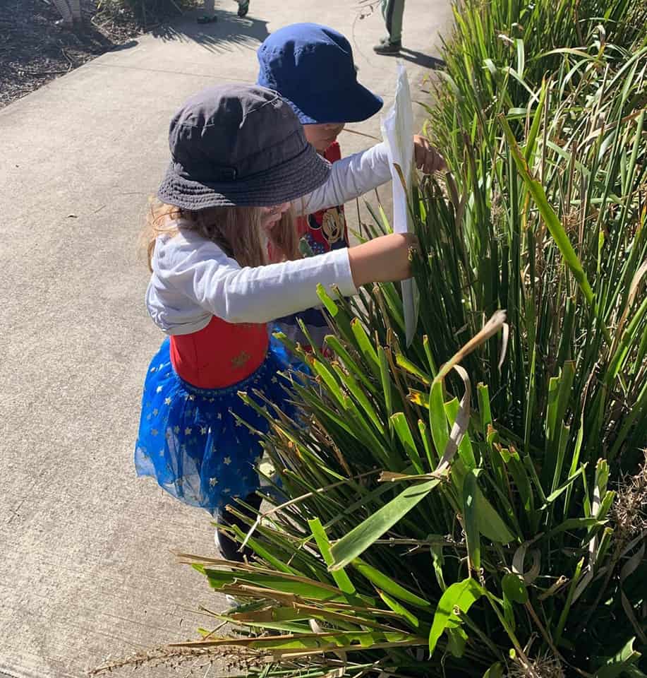 children hiding book in garden for book hide and seek