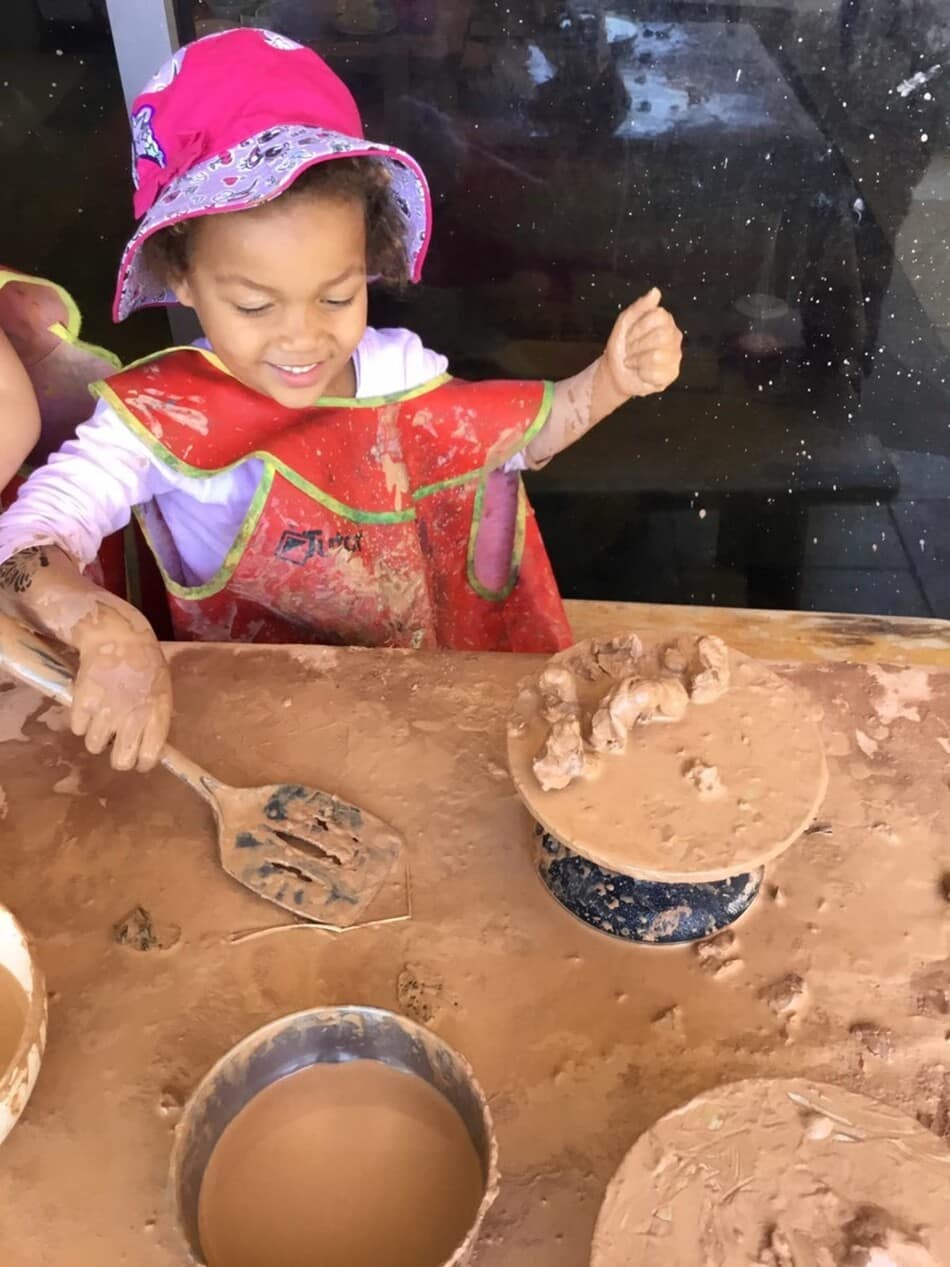 child playing with clay in bucket at Guardian Gungahlin