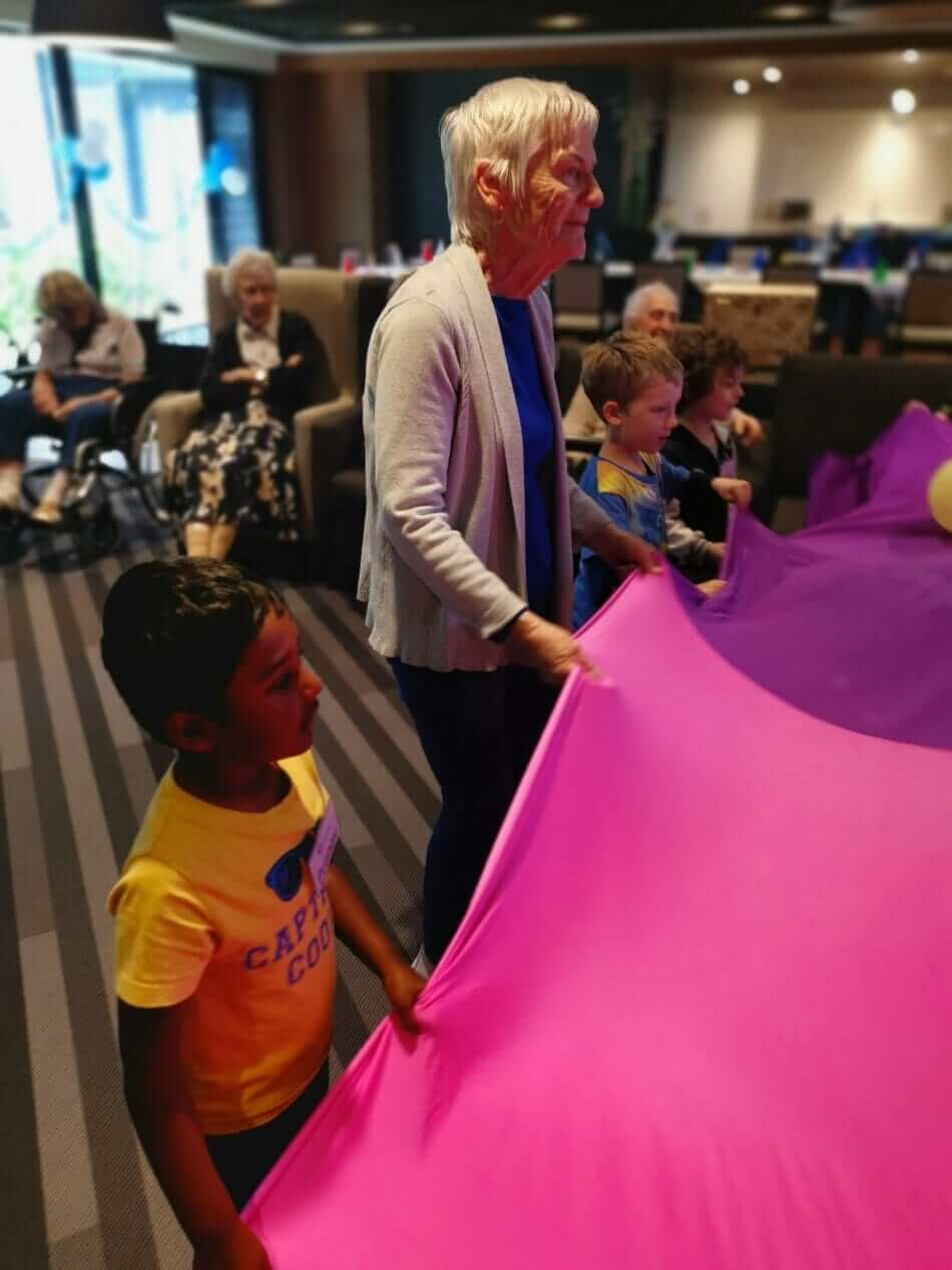 children and residents holding parachute at playgroup