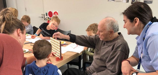children playing connect four with resident at intergenerational program