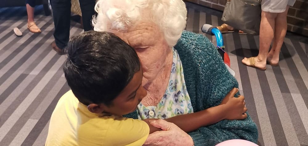 child and aged care resident hugging at playgroup