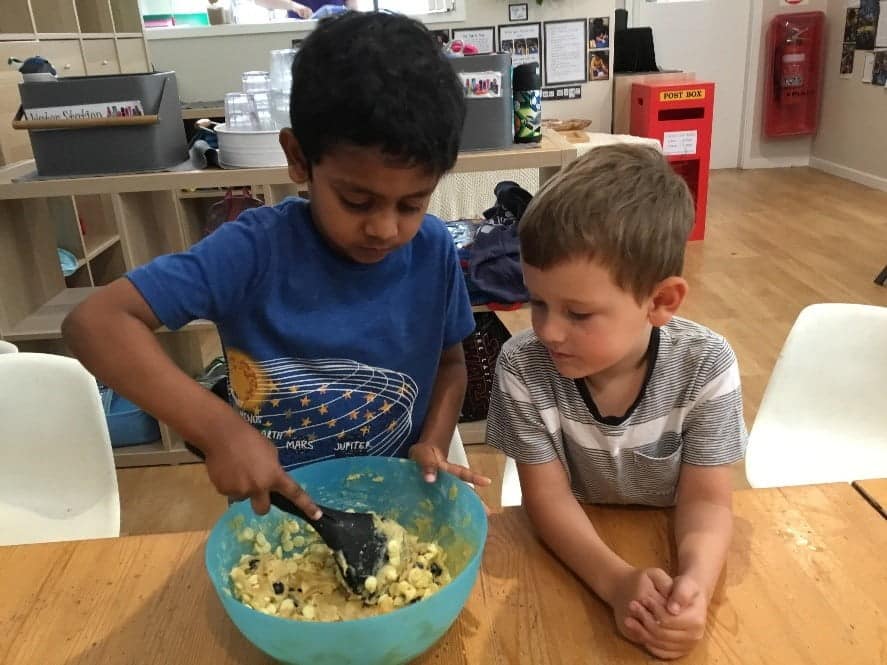 two children stirring cookie mix, baking for local fire brigade