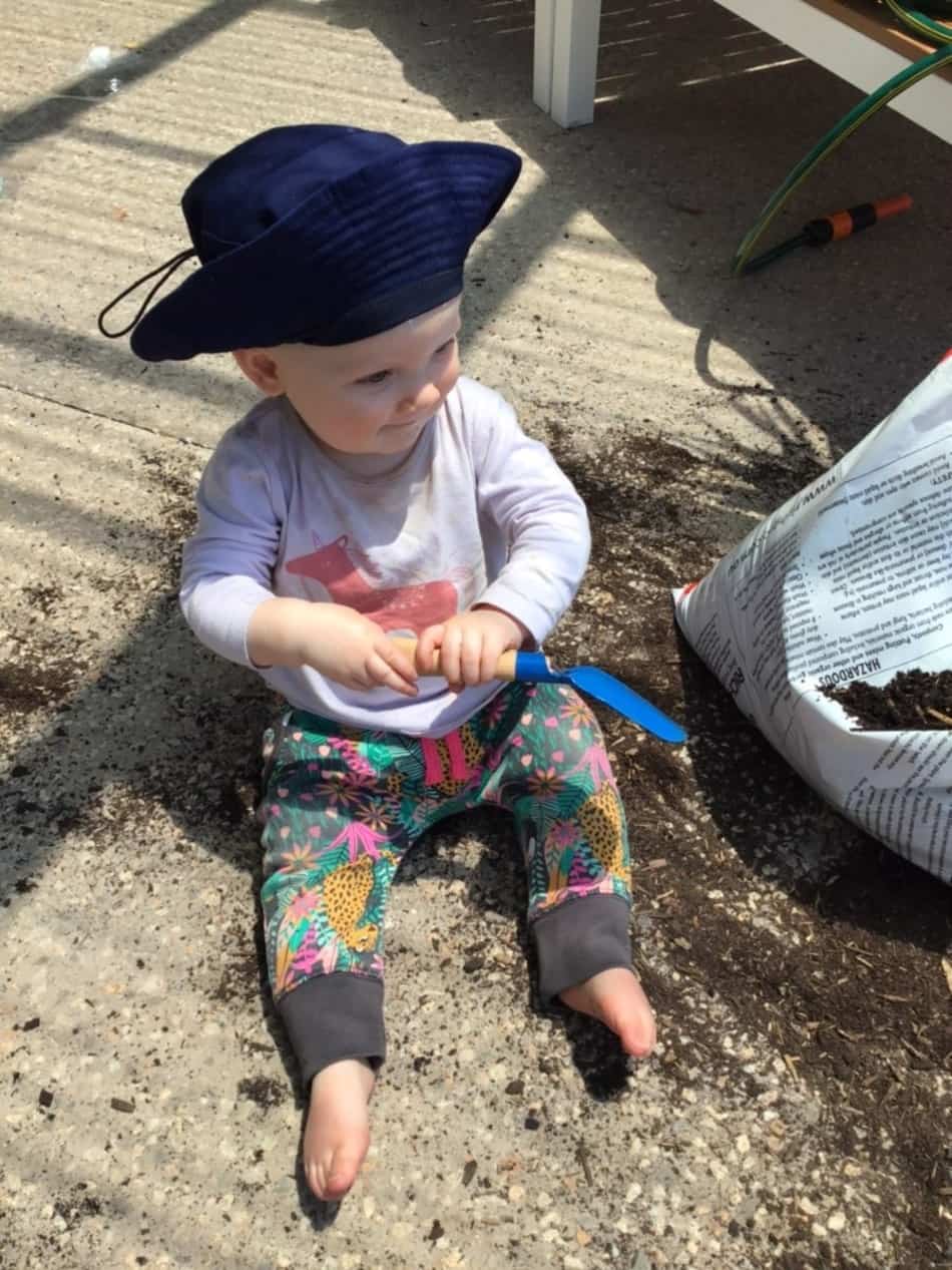 toddler helping pot plants in childcare experience