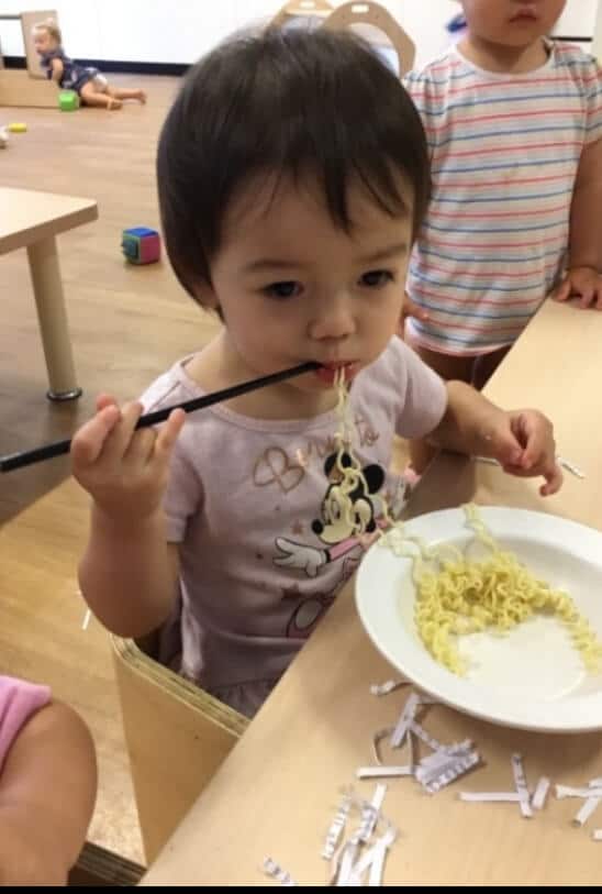 toddler eating noodles with chopsticks during Chinese New Year celebration