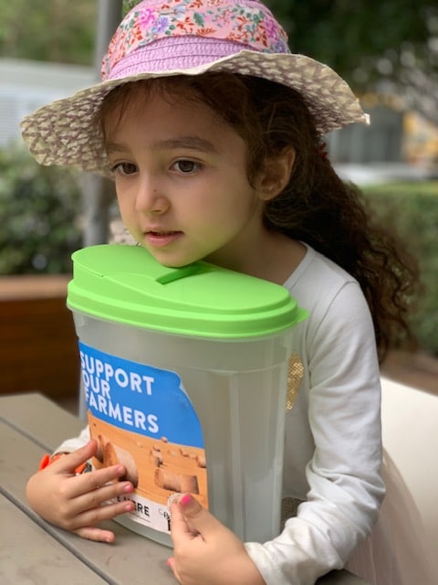 girl holding donation box for farmers fundraiser