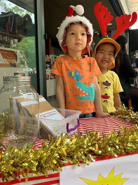 two boys wearing Christmas hats selling handmade cards for farmers fundraiser