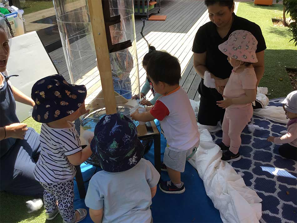 toddlers with educator testing the flight quality of cotton fluff