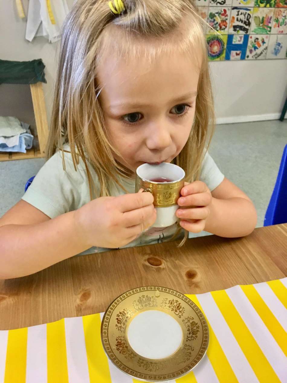 child sipping on tea during tea time