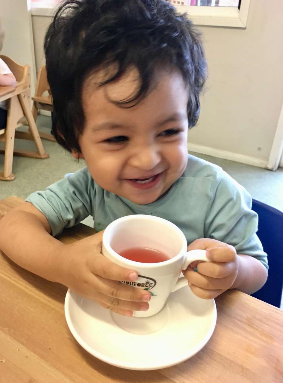 toddler smiling and drinking tea during tea time